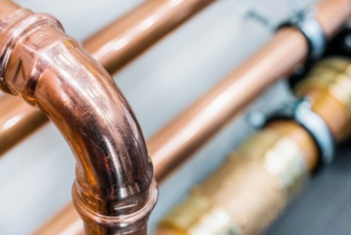 close-up-of-copper-pipes-in-residential-plumbing-system Detailed view of new copper plumbing pipes with fittings in a home